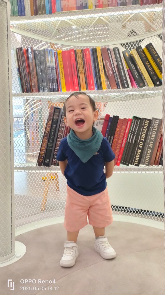little boy with book shelf behind